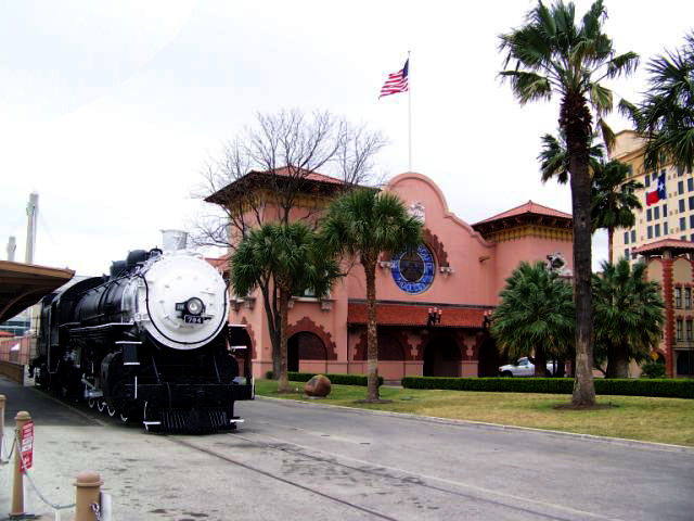 San Antonio's pink train station framed by palm trees and a vintage train