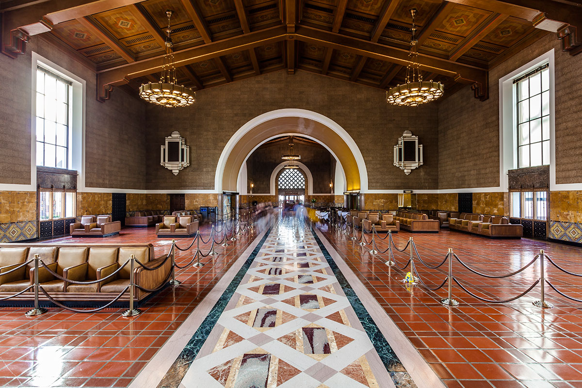 View inside the Los Angeles Train station with the colorful geometric tiles, benches and two chandeliers hanging from the wooden ceiling 