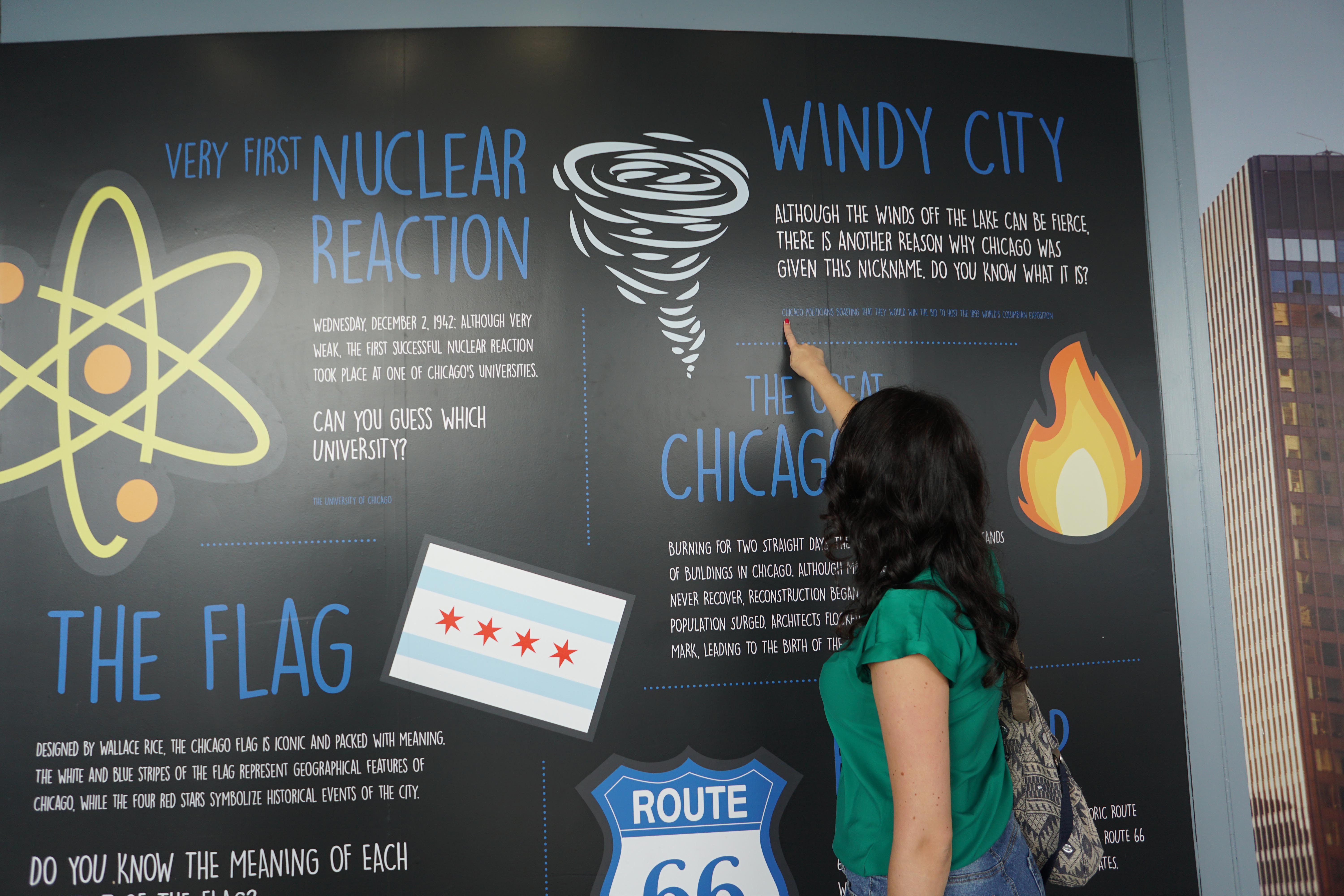 Woman pointing at a fun fact about the "Windy City" at The Willis Tower's Skydeck
