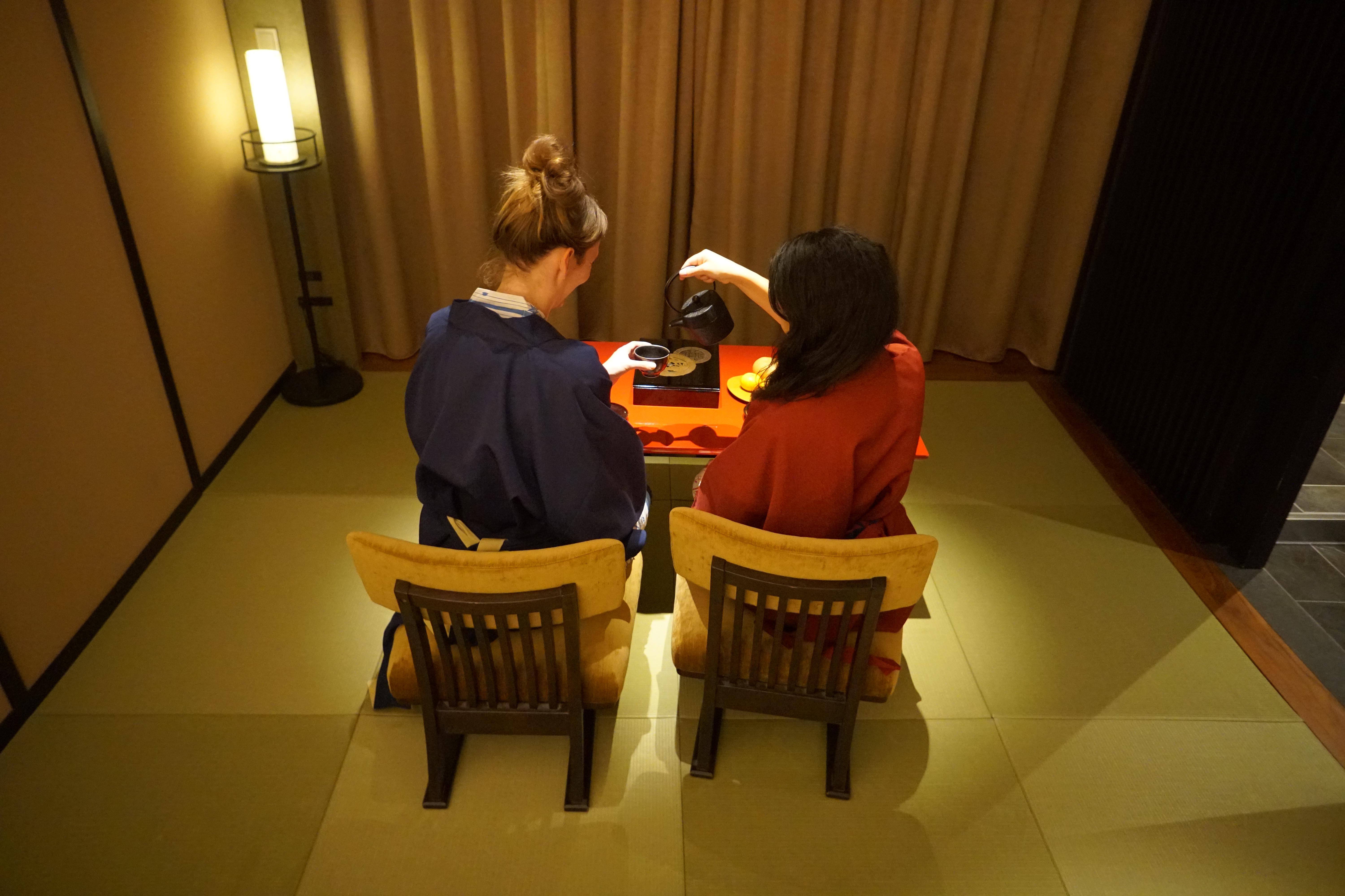 two girls having tea at the table on the matt in the room 