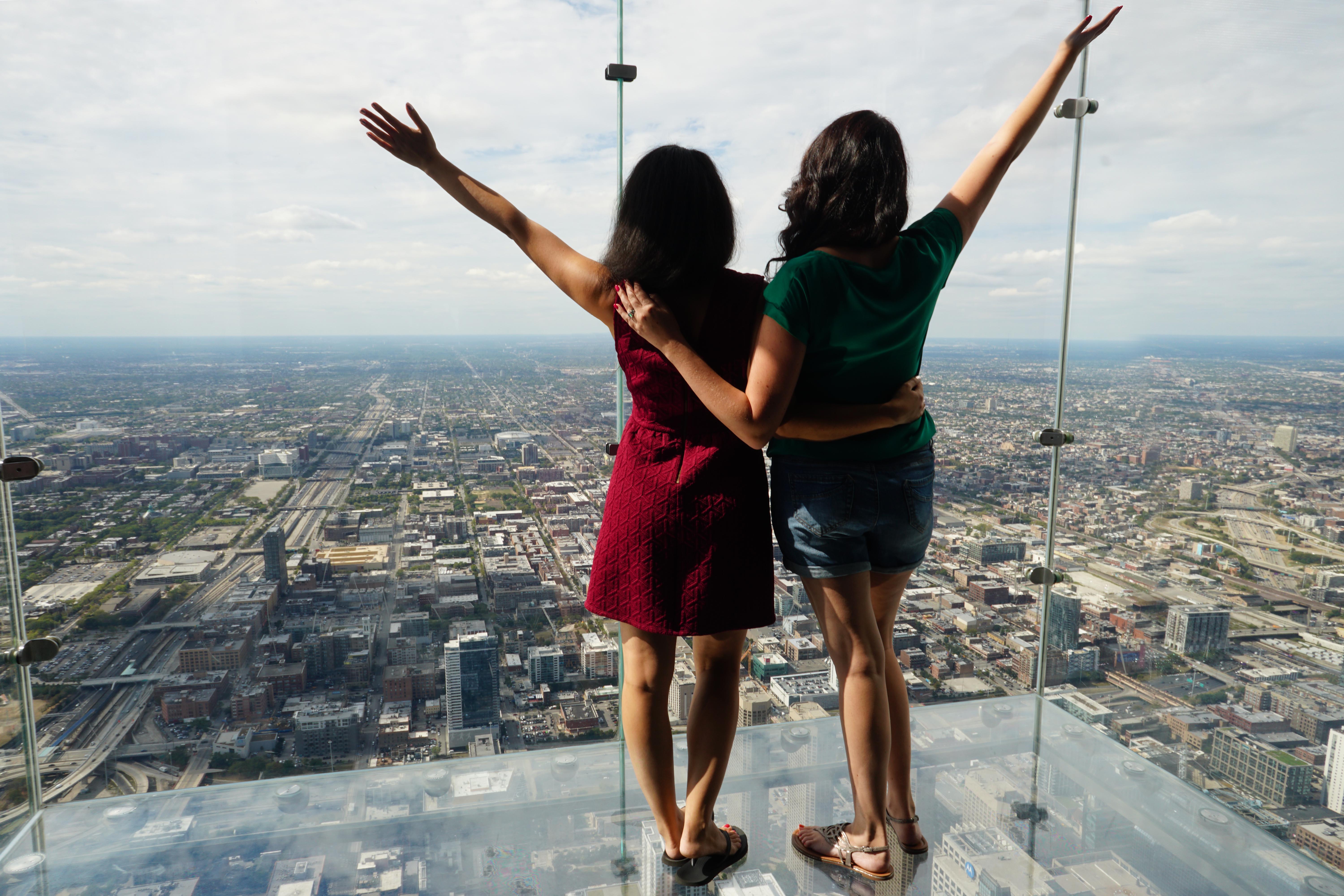 Women at Skydeck The Ledge looking out with arms up