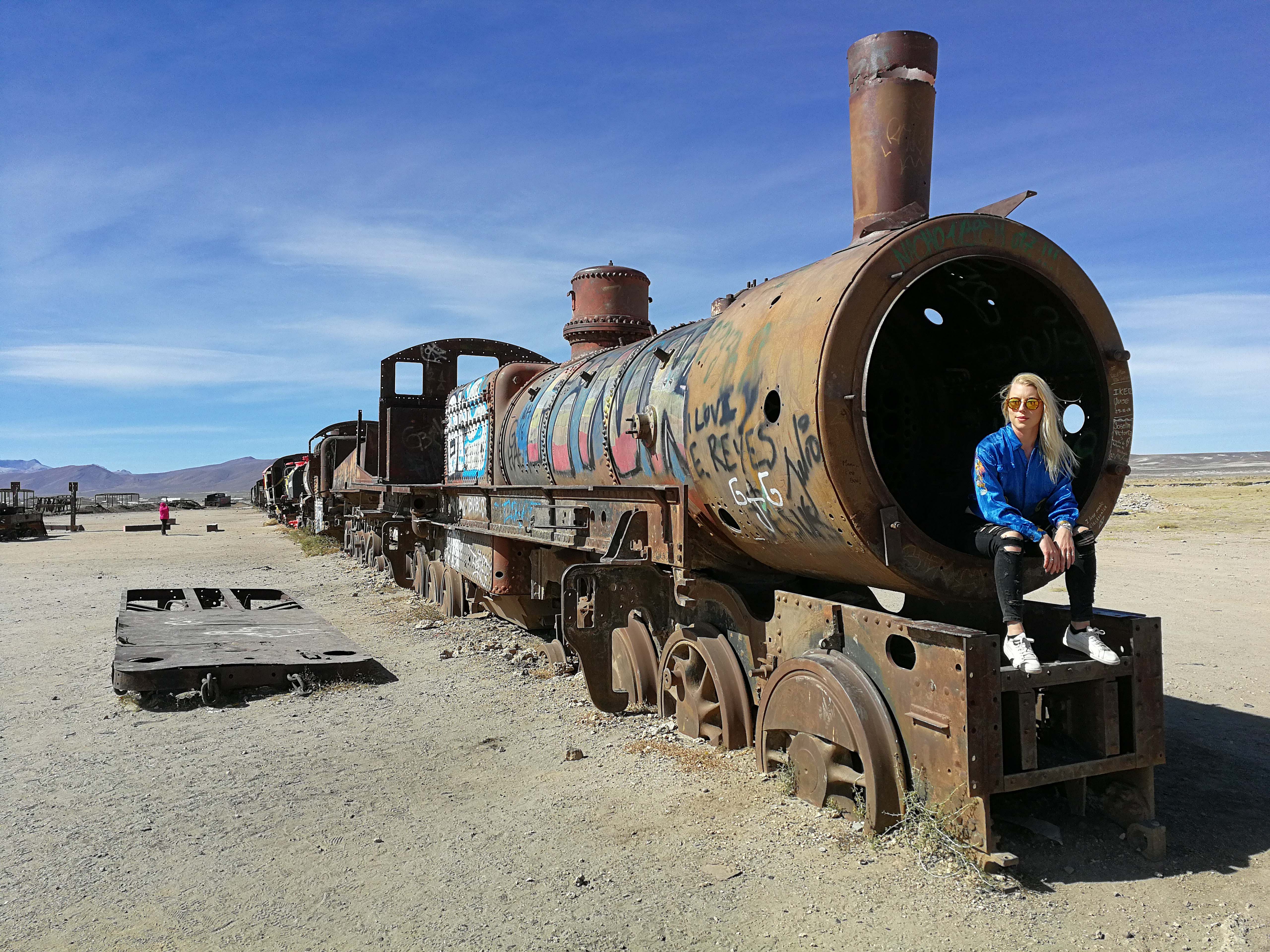 Louise sitting on the front of an abandoned train in the desert 