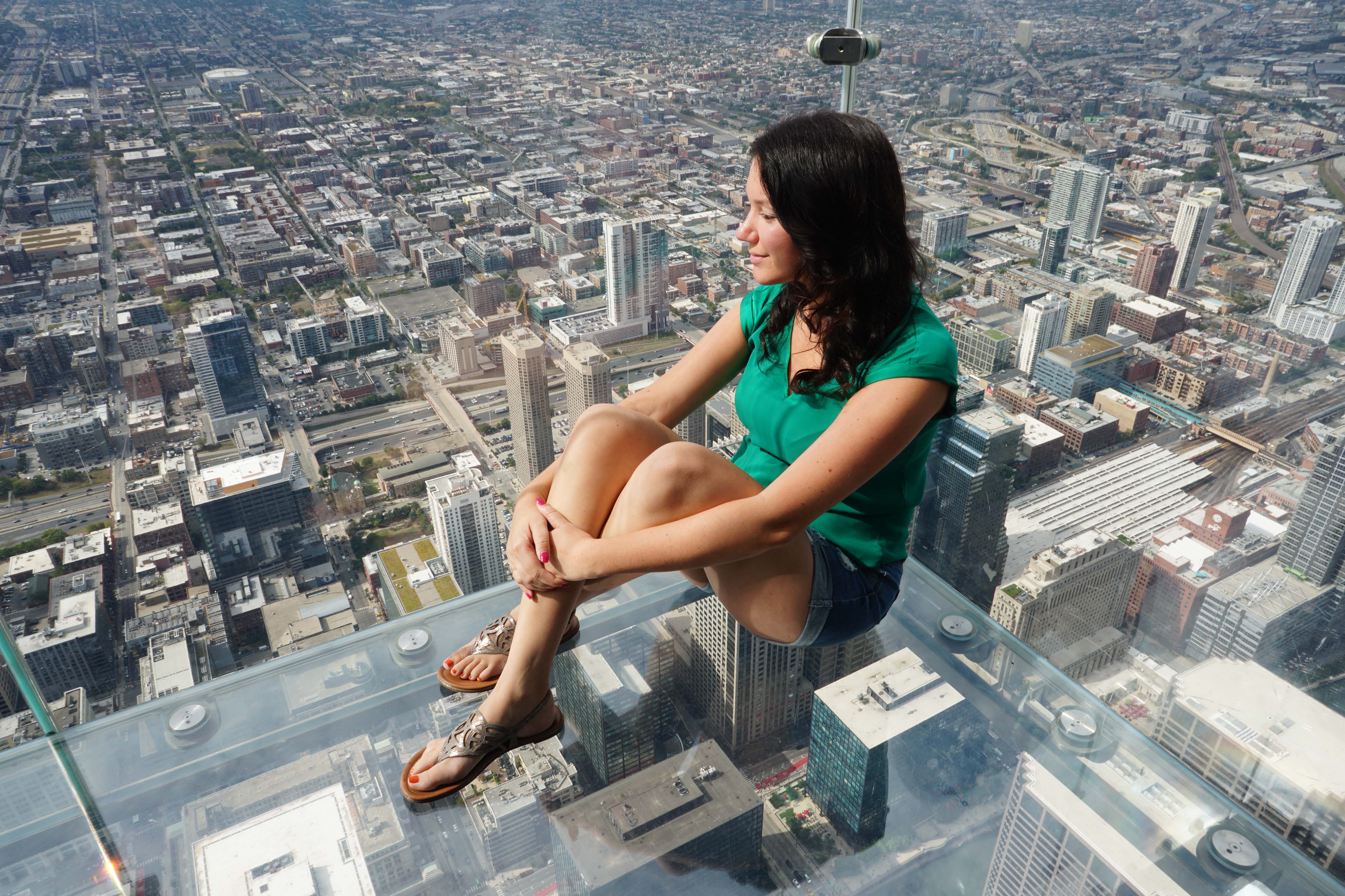 Woman sitting down on the dangerous looking Skydeck The Ledge