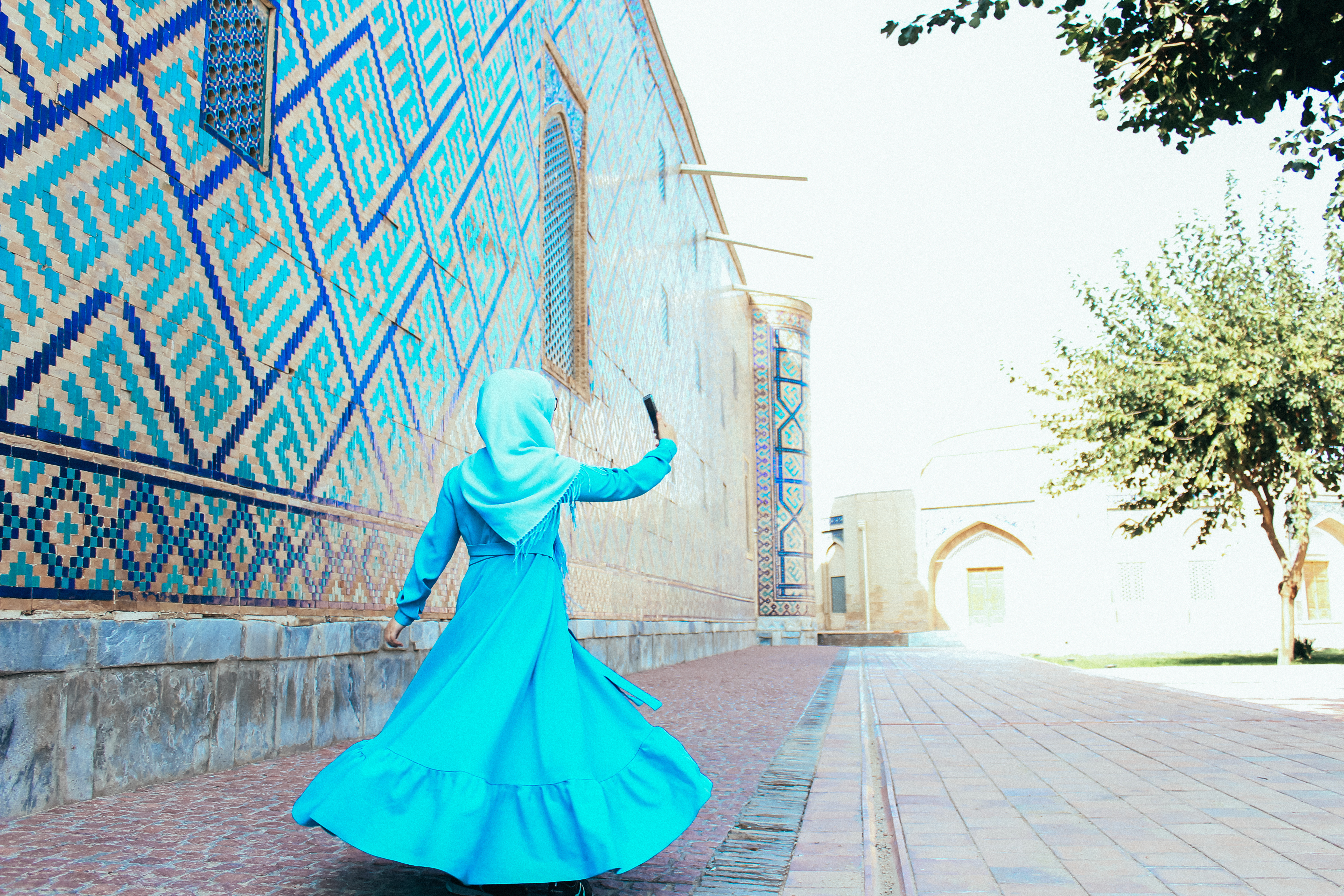 Muslim woman in a blue dress in Samarkand takes a selfie